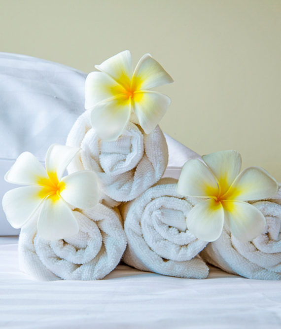 Rolled white towels with yellow and white flowers decorating them