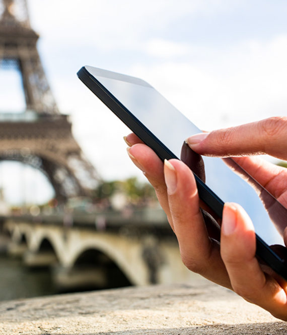 Hand holds mobile phone with Eiffel Tower in background