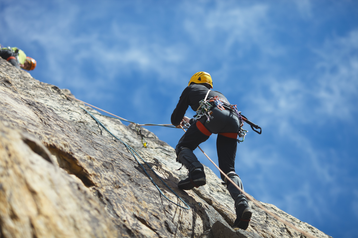 Climber climbs on the rock wall against a blue sky. Climbing gear. Climbing equipment.