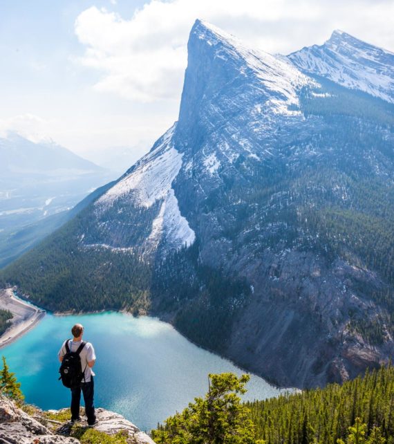 Traveler stands on overlook of mountain lake